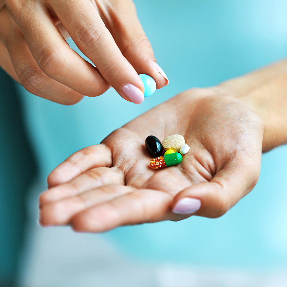 Closeup of hands holding a variety of supplements/vitamins