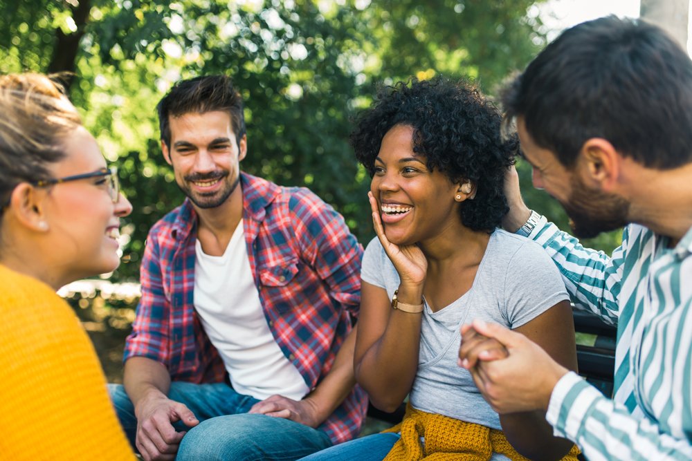 Woman wearing a hearing aid having a conversation with friends in a park