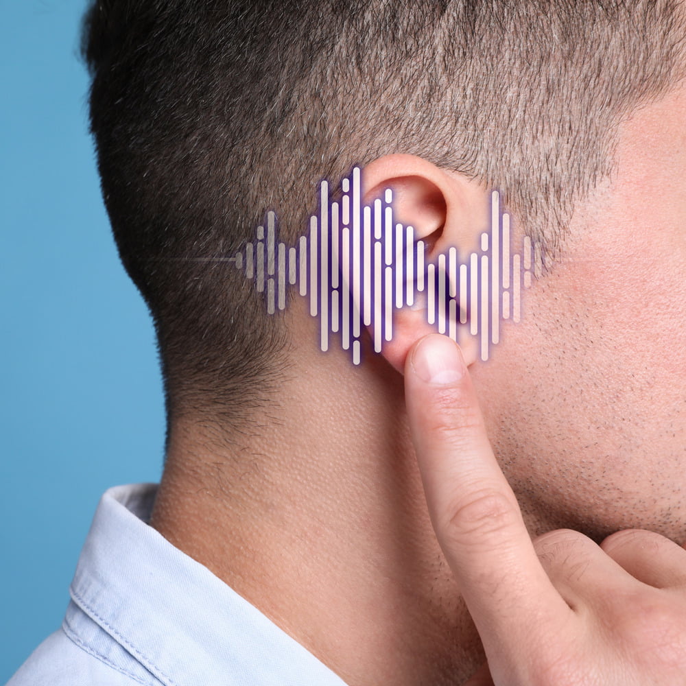 Man pointing to his ear; frequency waves