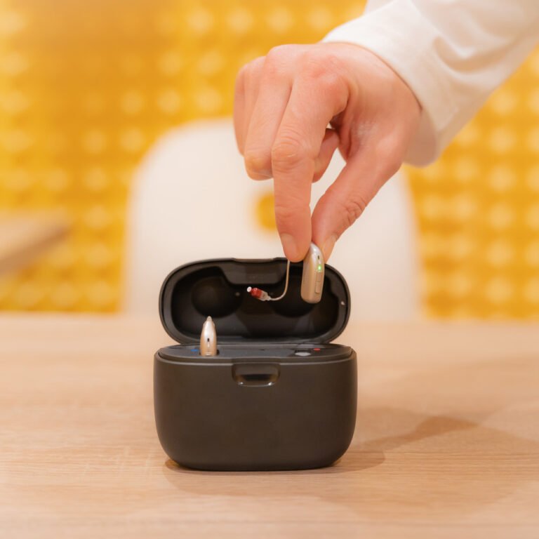 Audiologist's hand placing a hearing aid inside its charger.