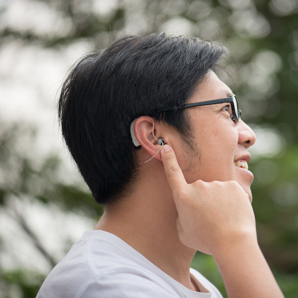 Asian man with hearing aid behind the ear outdoors